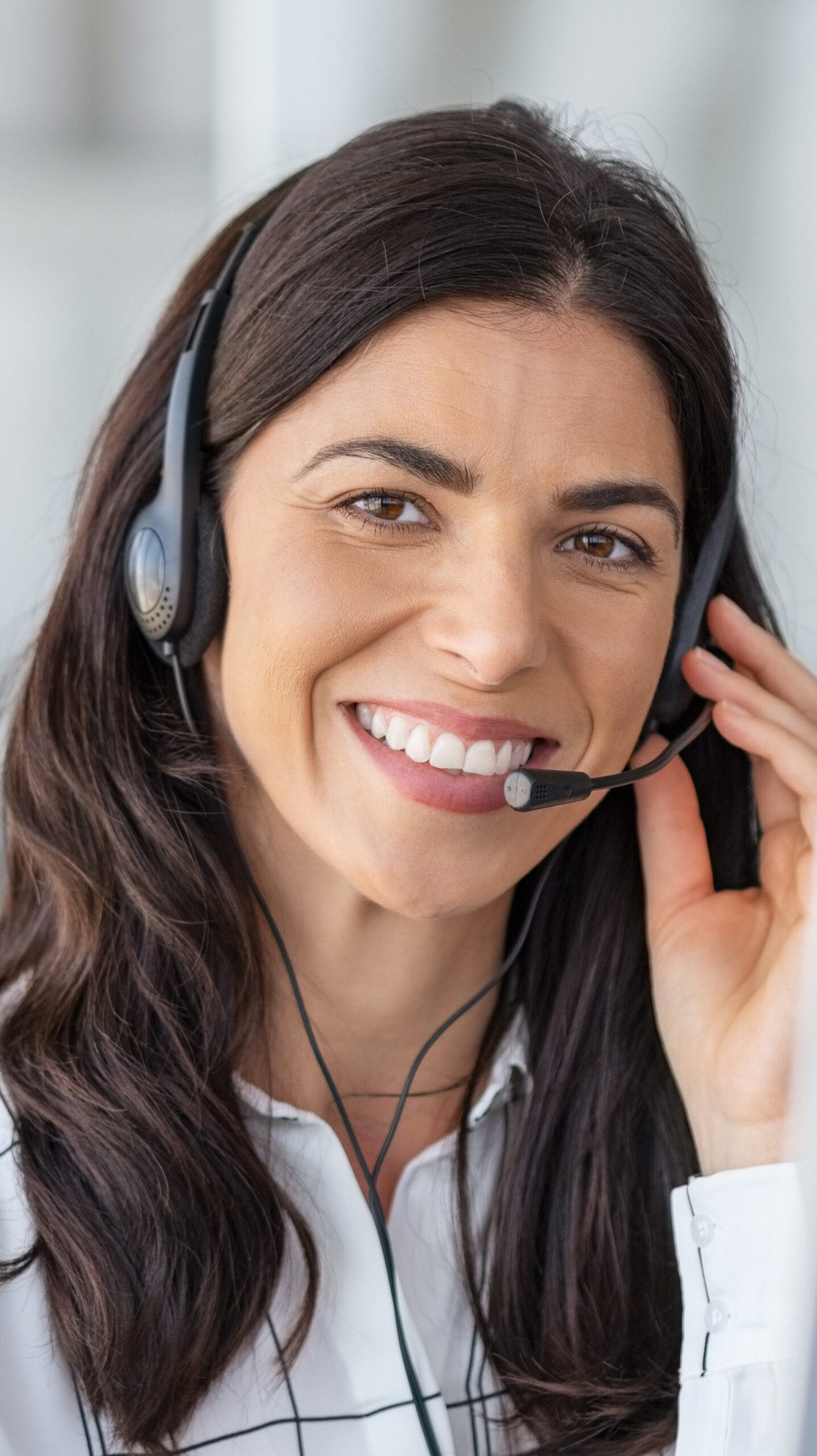 Smiling woman with long, dark hair and a phone headset